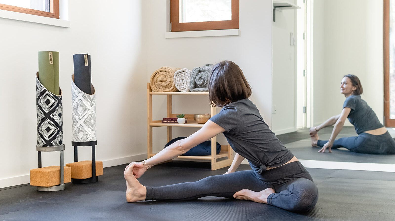 yogis stretching in front of a mirror at their home gym with props and sustainable prop storage by Mache