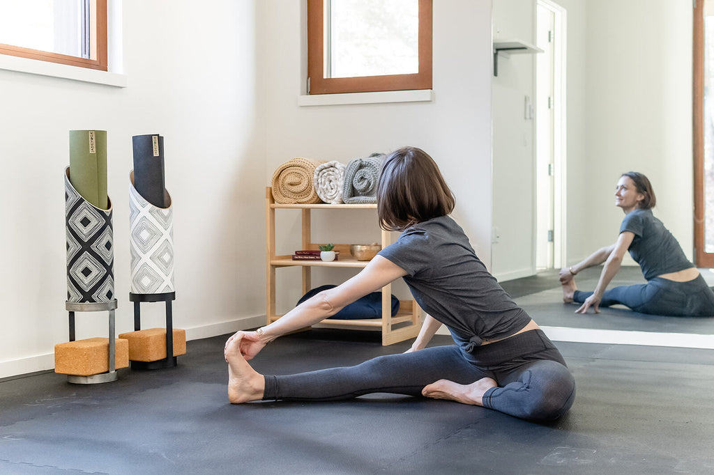 yogis stretching in front of a mirror at their home gym with props and sustainable prop storage by Mache