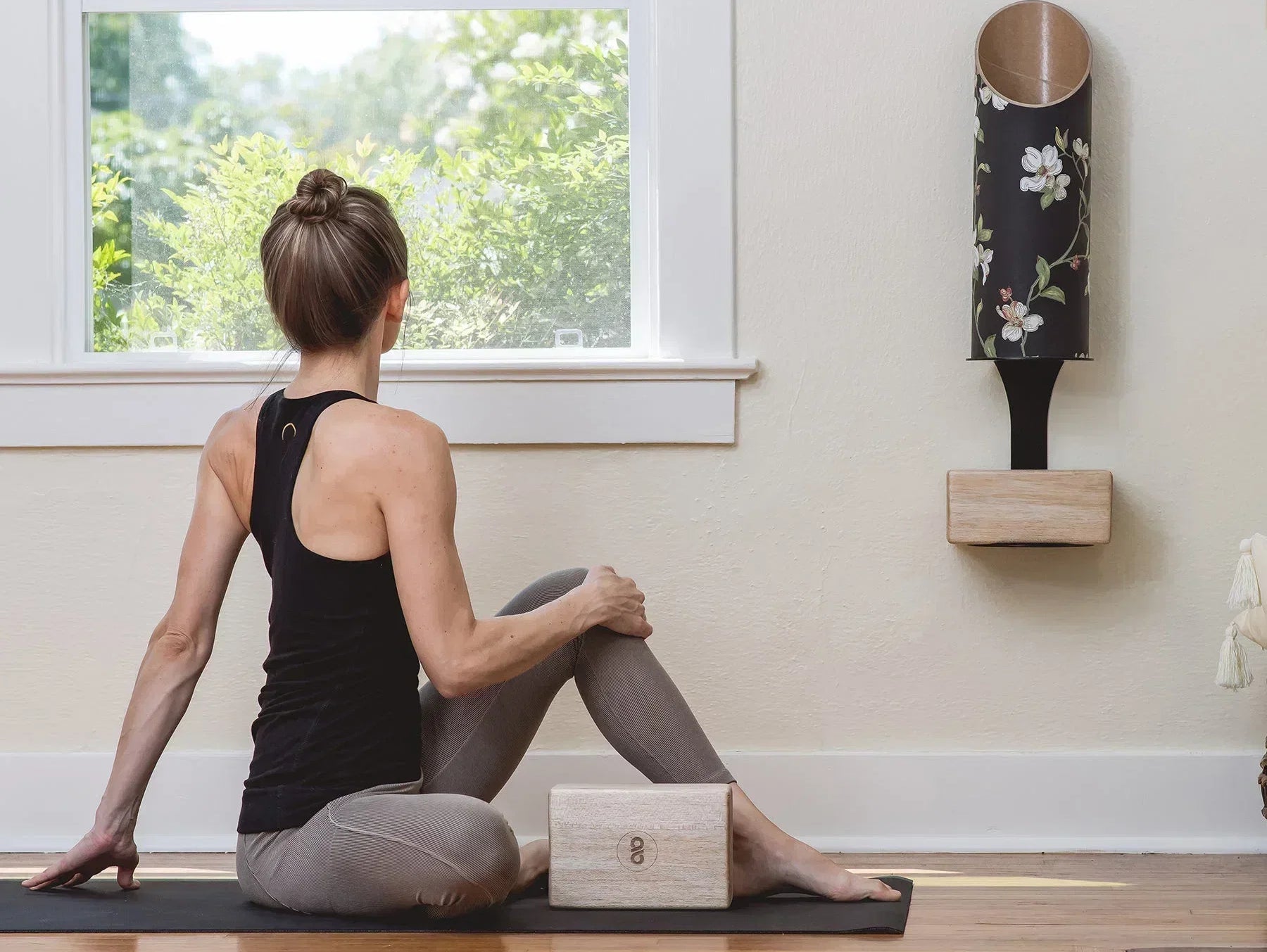 Woman practicing yoga on an eco-friendly yoga mat beside a yoga block and Mache Homi Wall Bracket storage.