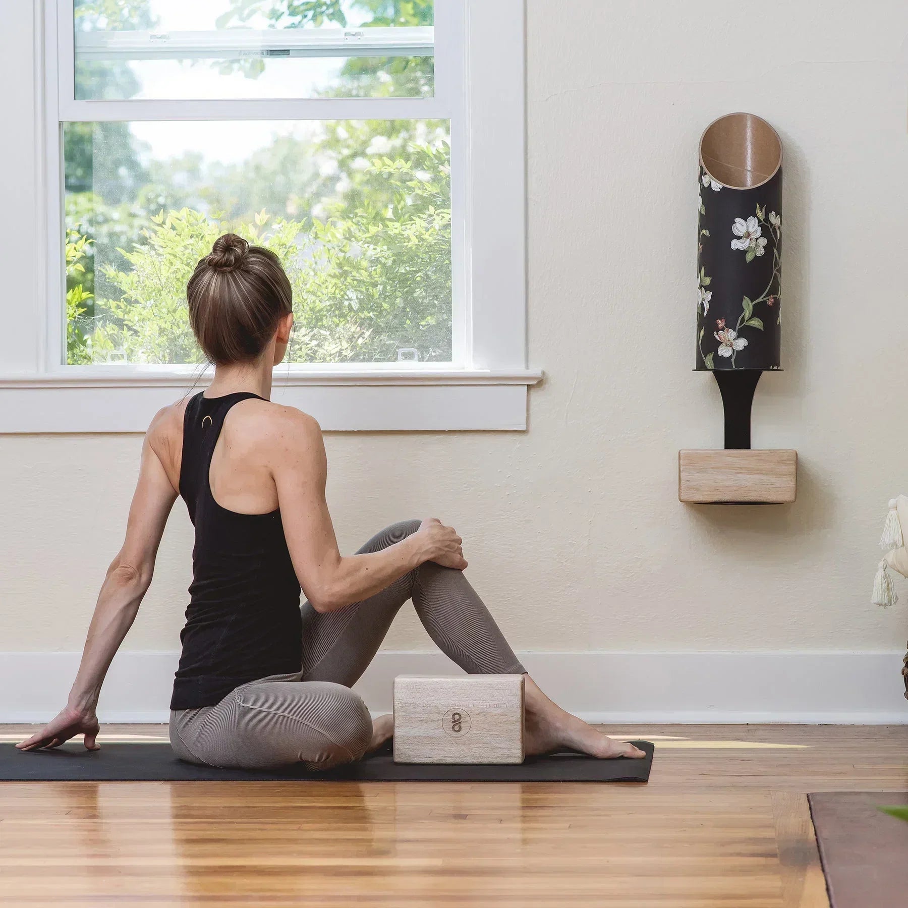 Woman practicing yoga on an eco-friendly yoga mat beside a yoga block and Mache Homi Wall Bracket storage.