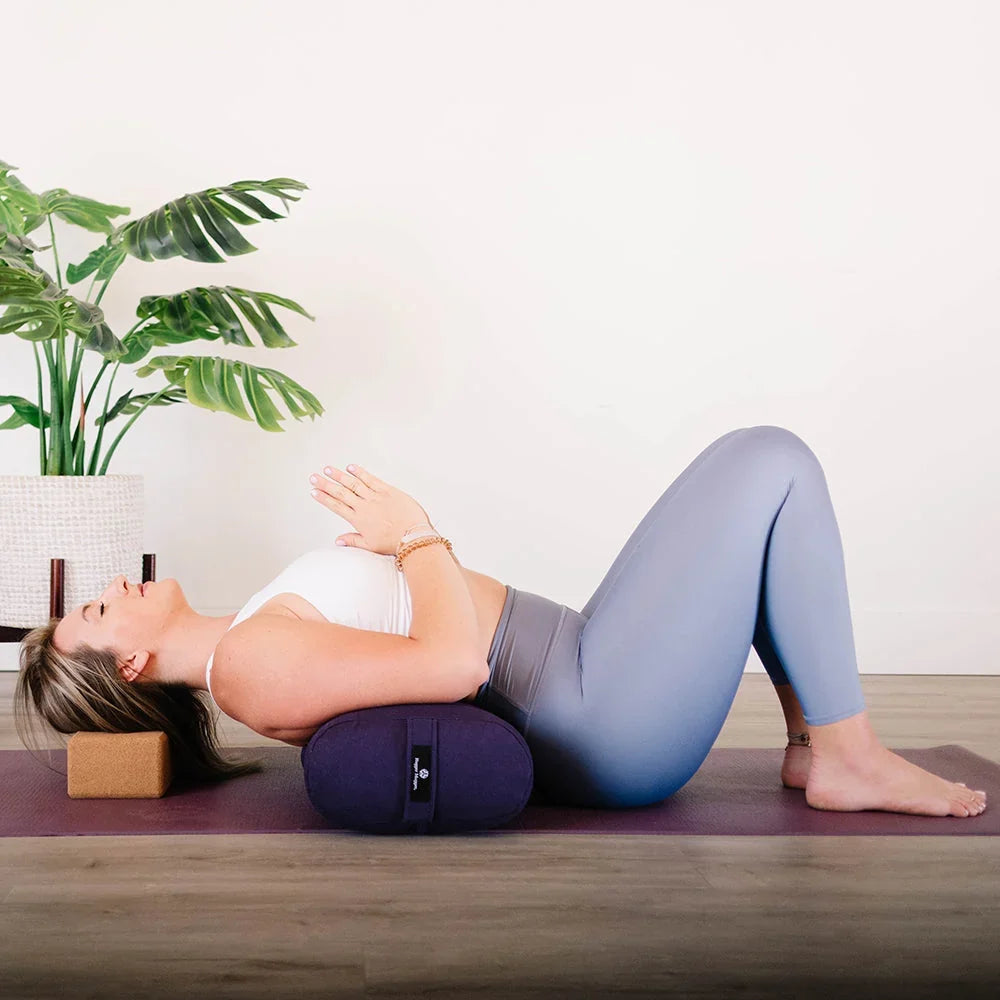 Woman using Mache eco-friendly cotton-covered yoga bolster to support her spine during a beginner-friendly reclined pose.