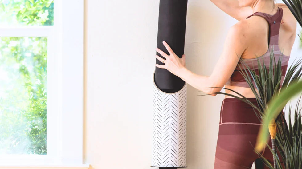 Woman using Mache wall-mounted yoga storage with yoga blocks and an eco-friendly yoga mat for a zen yoga setup.