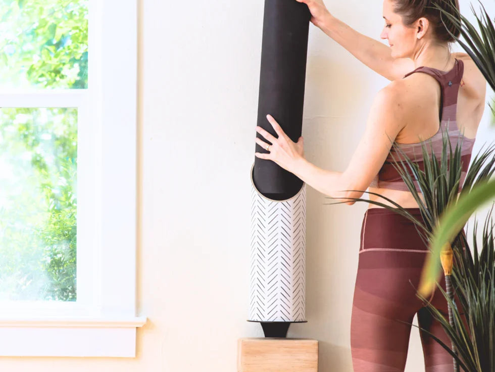 Woman using Mache wall-mounted yoga storage with yoga blocks and an eco-friendly yoga mat for a zen yoga setup.
