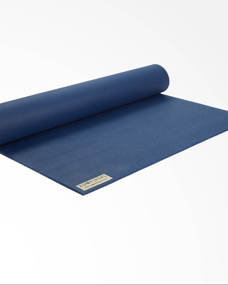 Rolling out midnight blue yoga mat on a white background