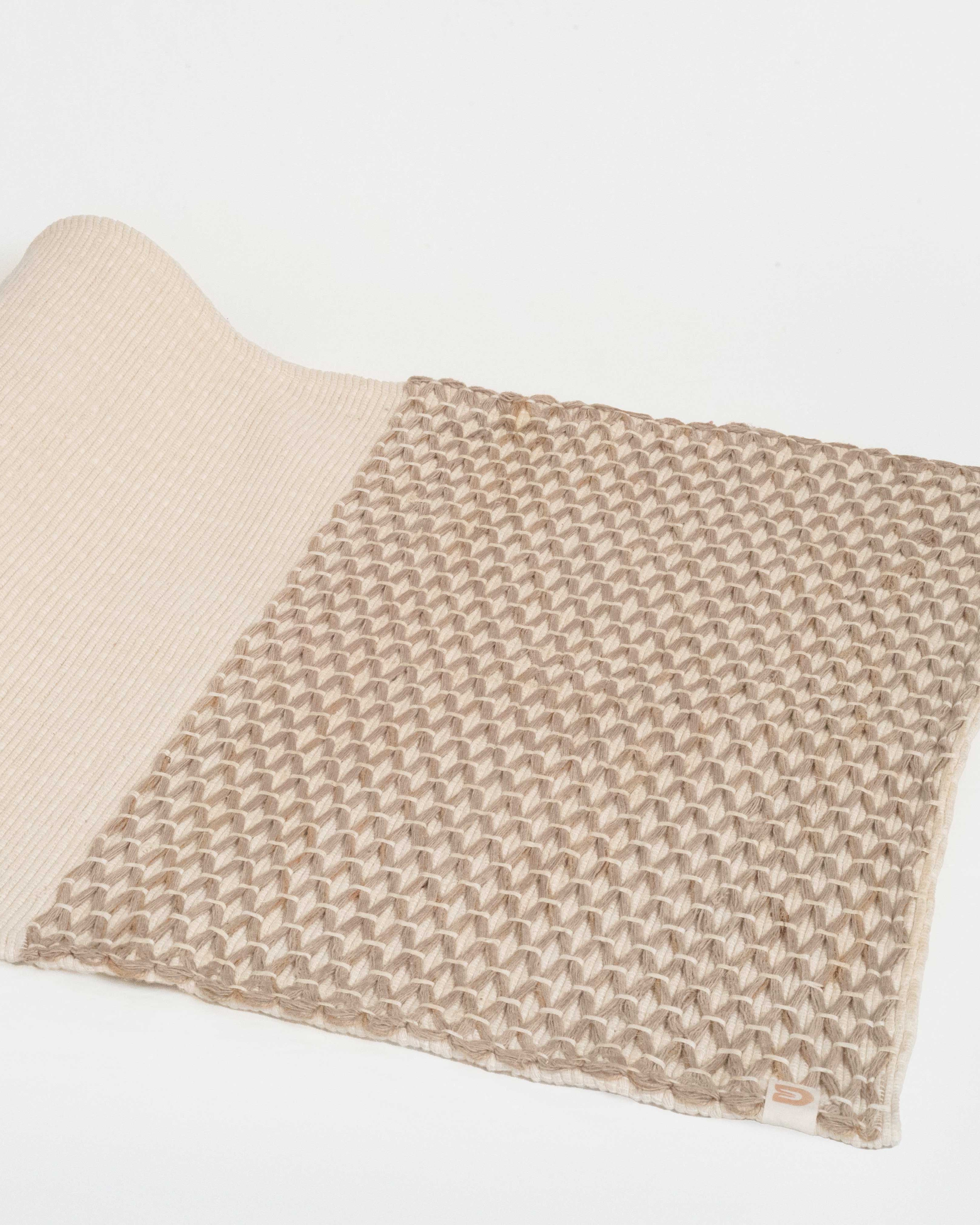 Folded beige and brown woven blanket on a white background