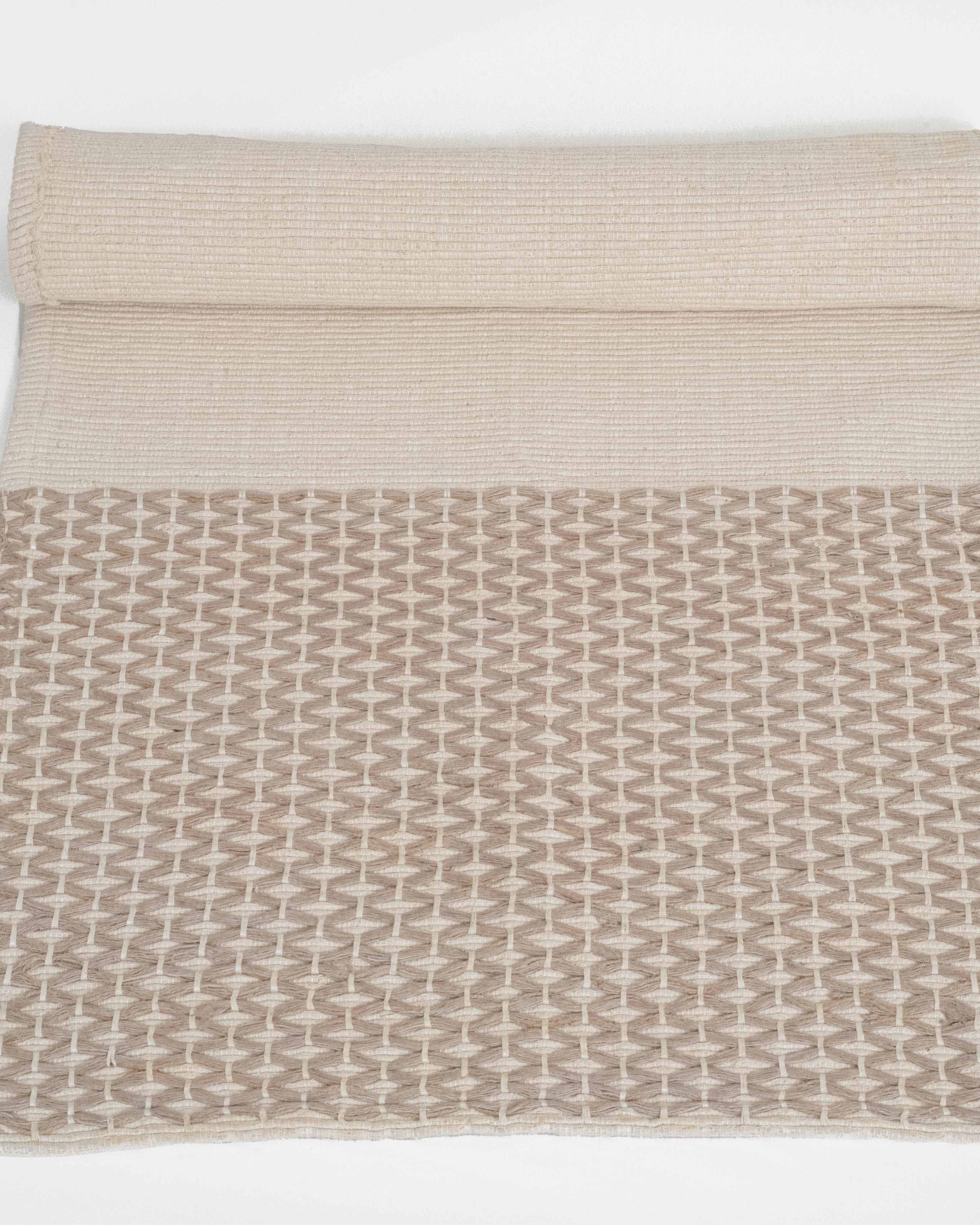 Textured beige blanket with geometric pattern on a white background
