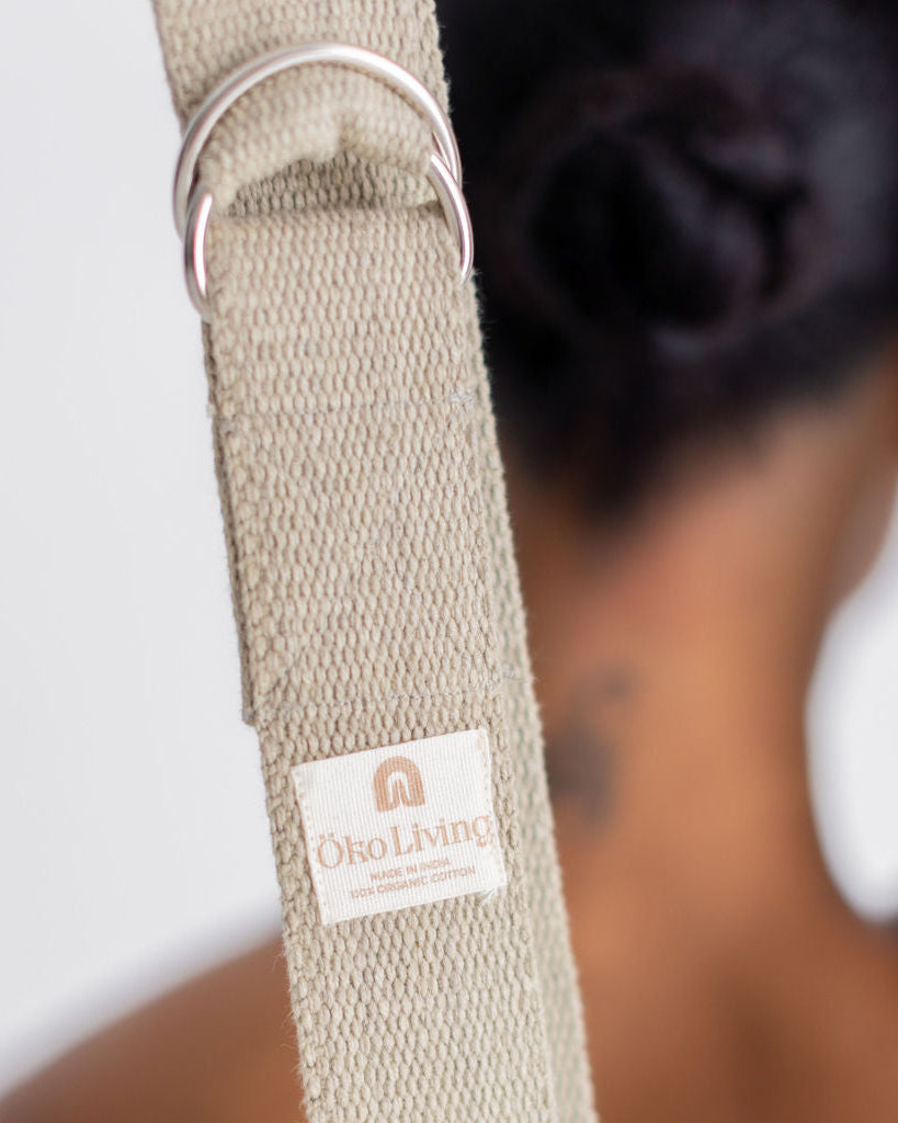 Beige yoga strap with a brand label on a blurred background