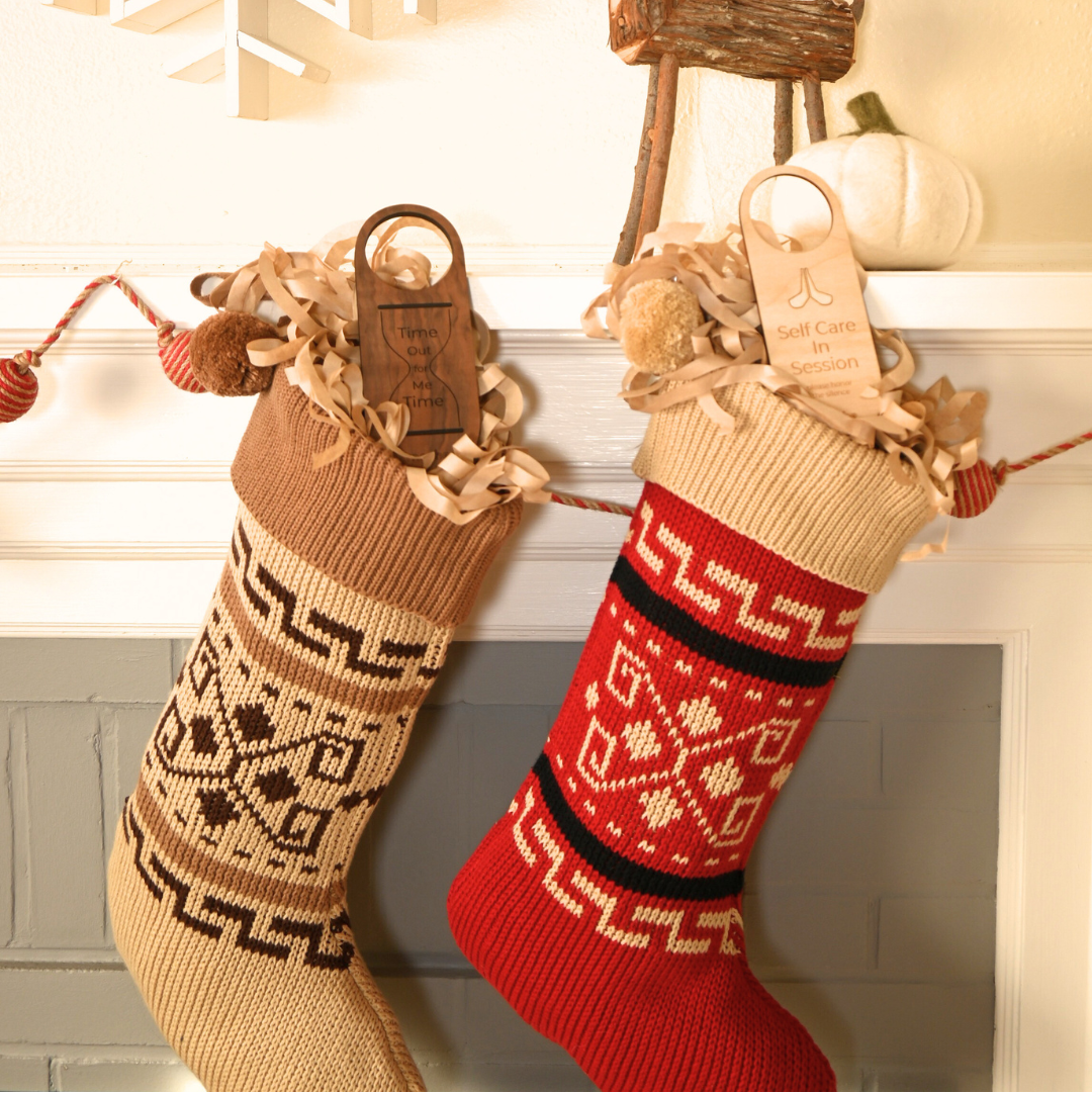 Two Christmas stockings, one red and one beige with patterns, hanging on a fireplace mantle.