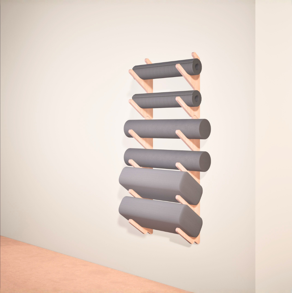 Wall-mounted yoga mat rack with yoga bolster pillows and foam rollers on a plain wall.