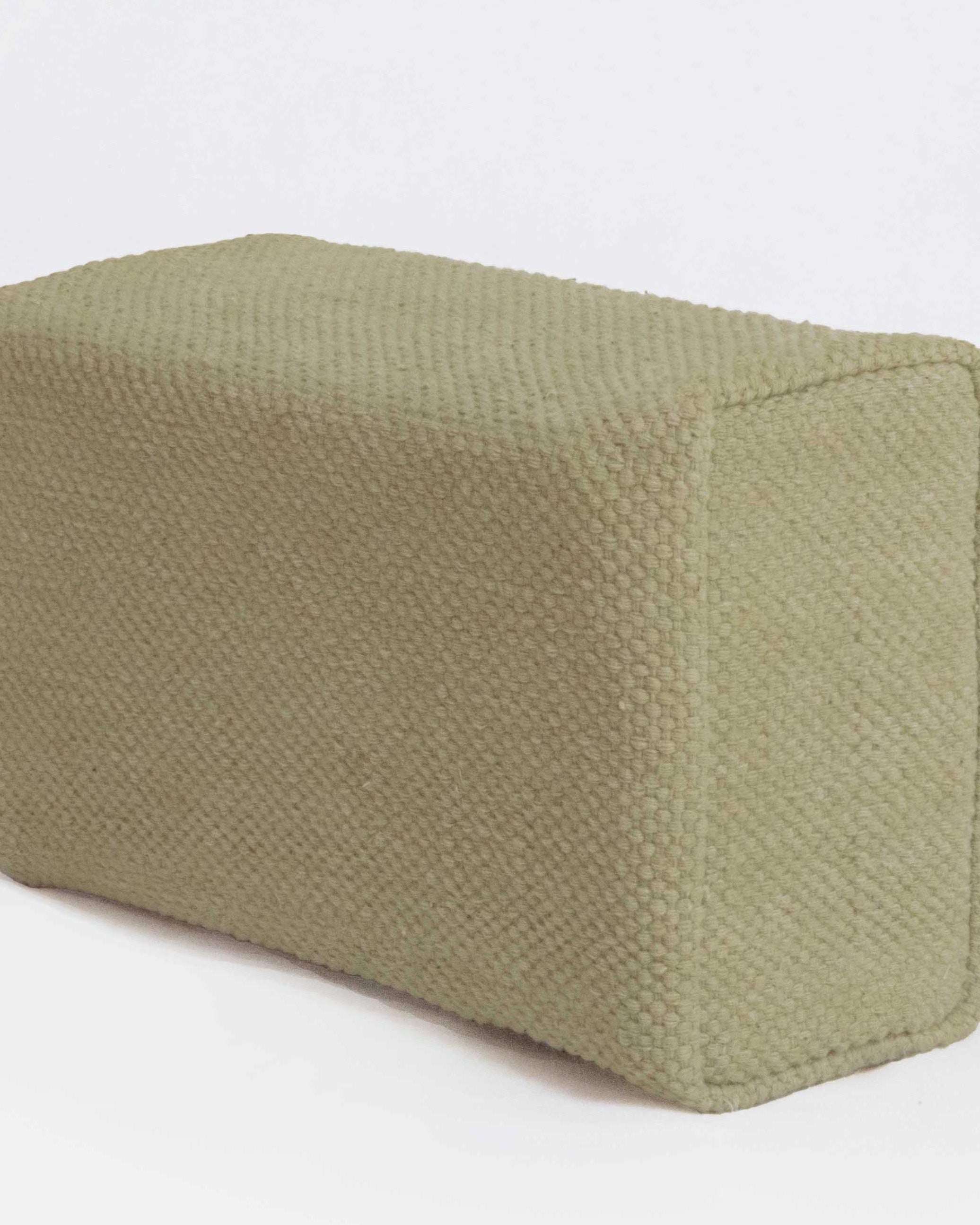 Green fabric yoga brick on a white background