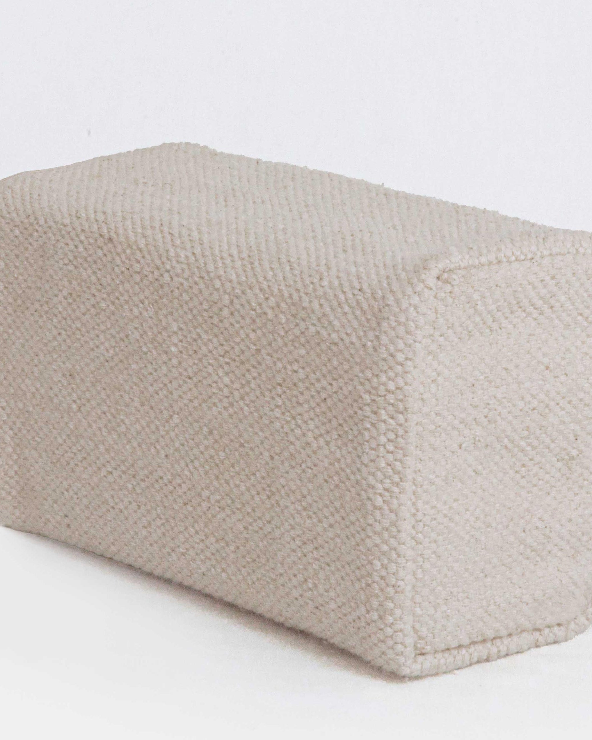 Textured beige fabric yoga block on a white background