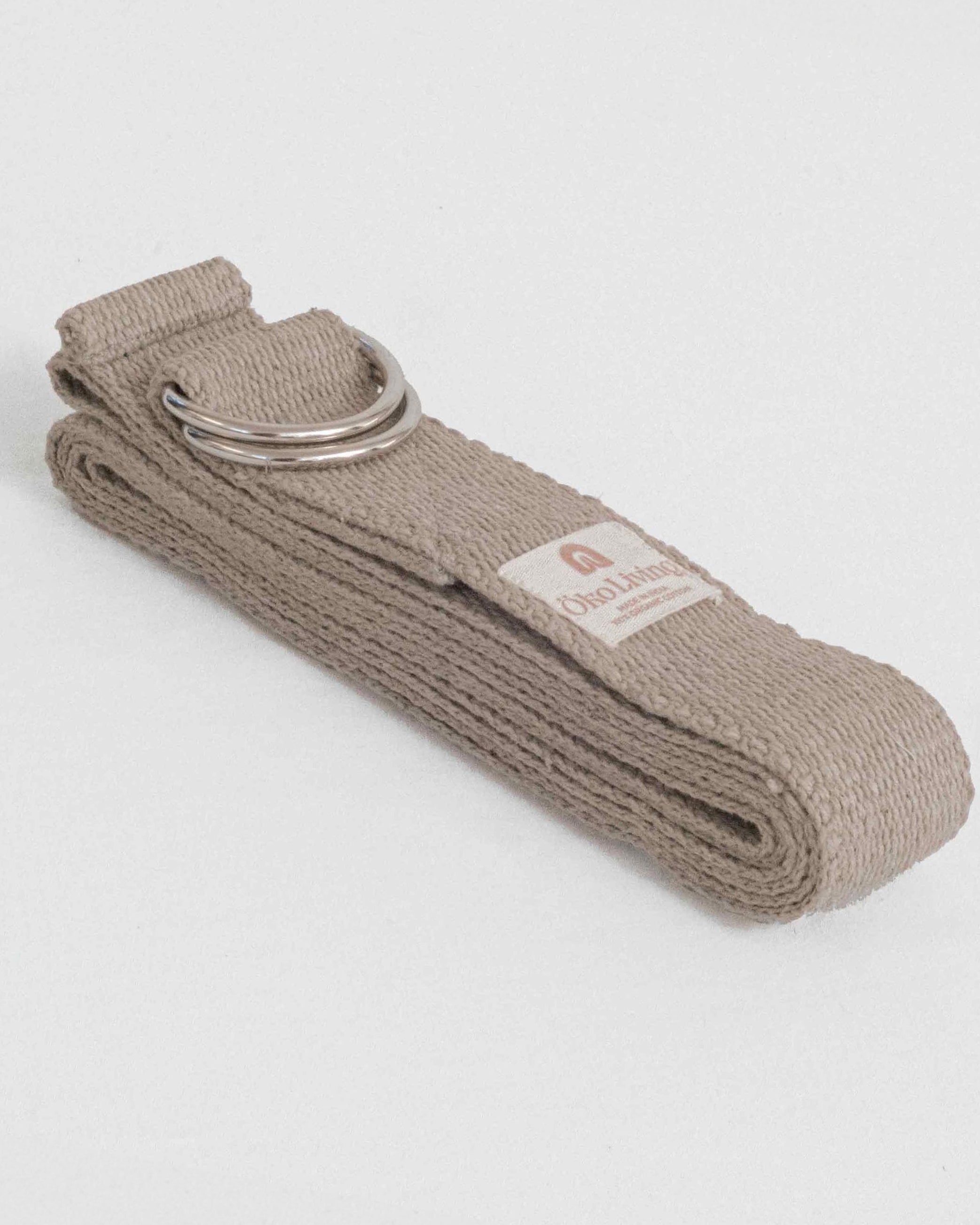 Beige yoga strap with a metal ring on a light gray background