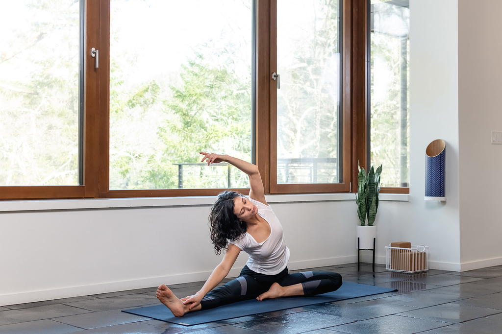 woman practicing yoga in front of a window in a home yoga studio with sustainable yoga prop storage