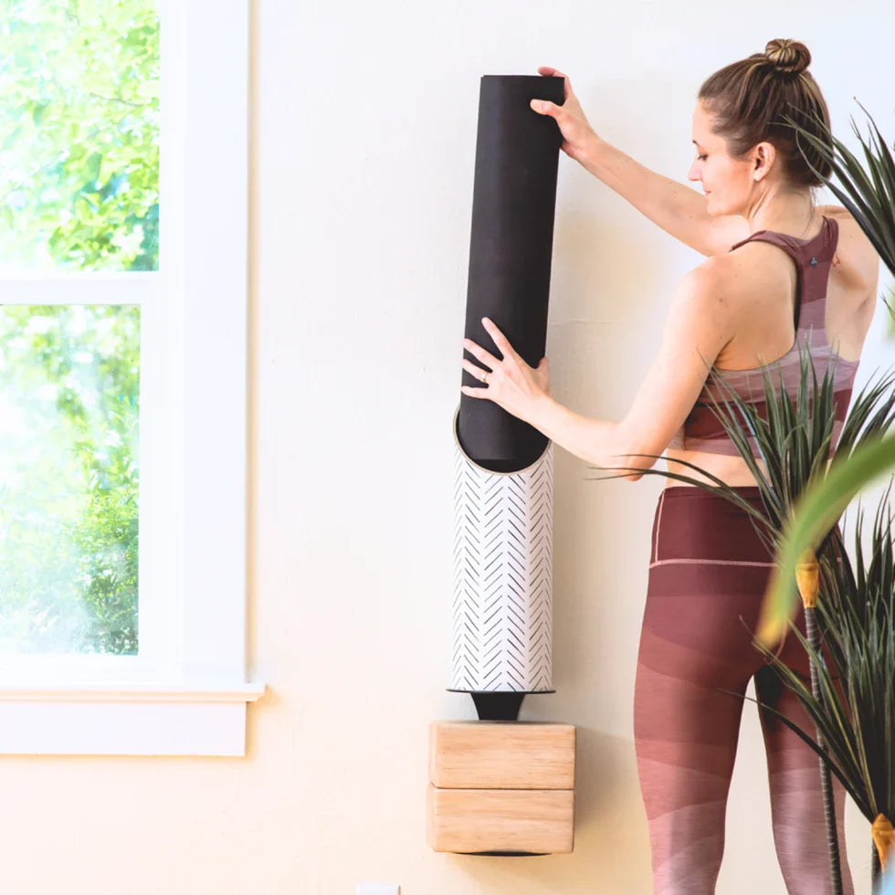 Woman using Mache wall-mounted yoga storage with yoga blocks and an eco-friendly yoga mat for a zen yoga setup.