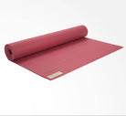 Rolling out raspberry-colored yoga mat on a white background