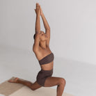 Person in a yoga pose on a mat with a plain background