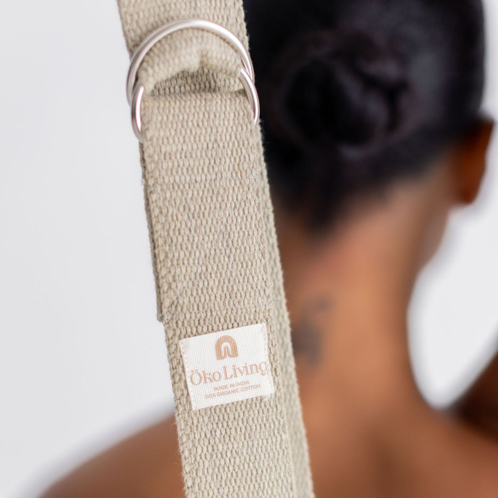 Beige yoga strap with a brand label on a blurred background