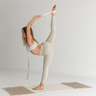 Person performing a yoga pose with a strap on a plain background