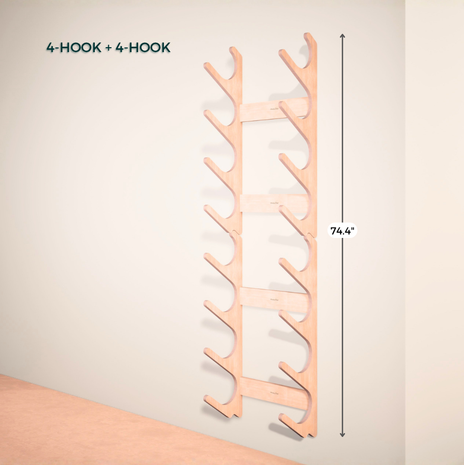 Wooden wall-mounted yoga mat rack with four hooks on a plain wall.