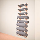 Wall-mounted yoga rack with gray yoga mats, foam rollers and yoga bolster cushions on against a plain wall.