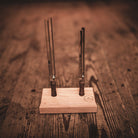 Two metal tuning forks on a wooden stand against a wooden background
