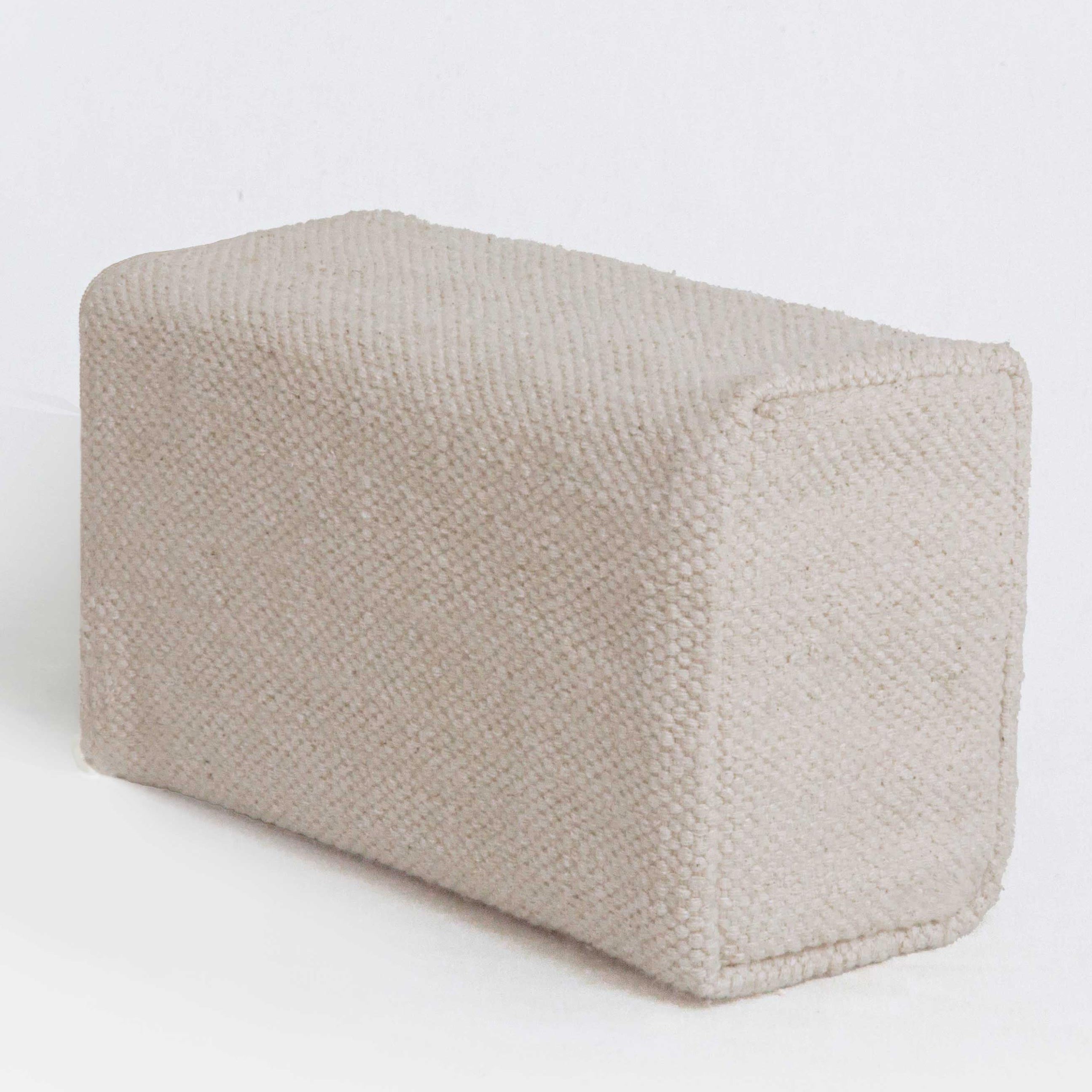 Textured beige fabric yoga block on a white background
