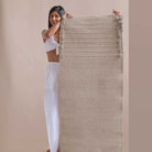 Woman holding a textured fabric yoga mat against a beige background