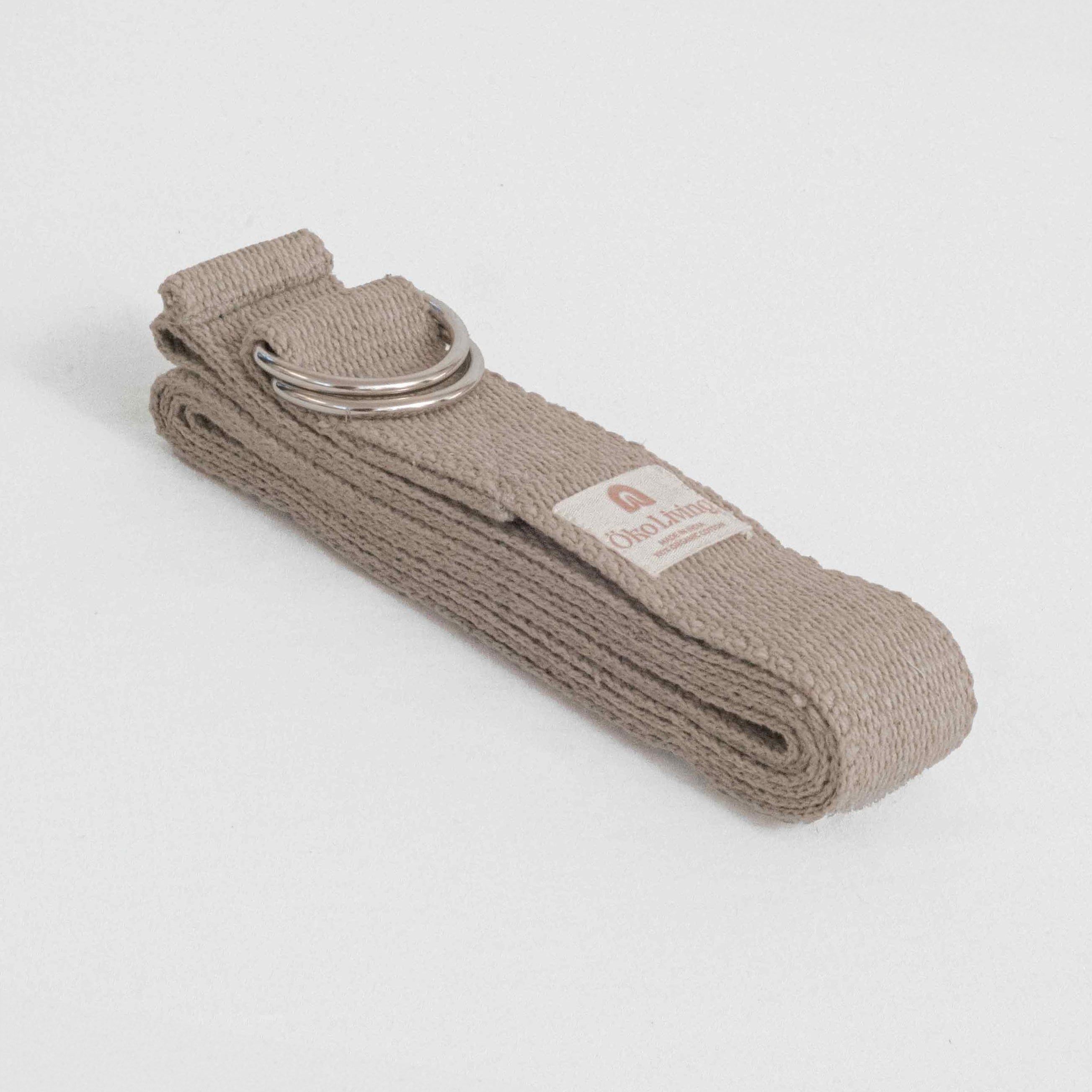 Beige yoga strap with a metal ring on a light gray background